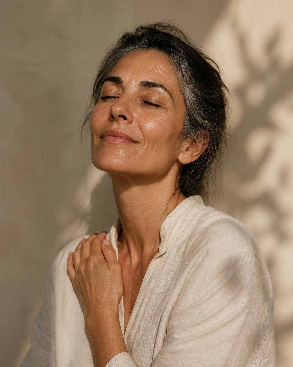 Mulher madura de expressão serena, iluminada por luz natural